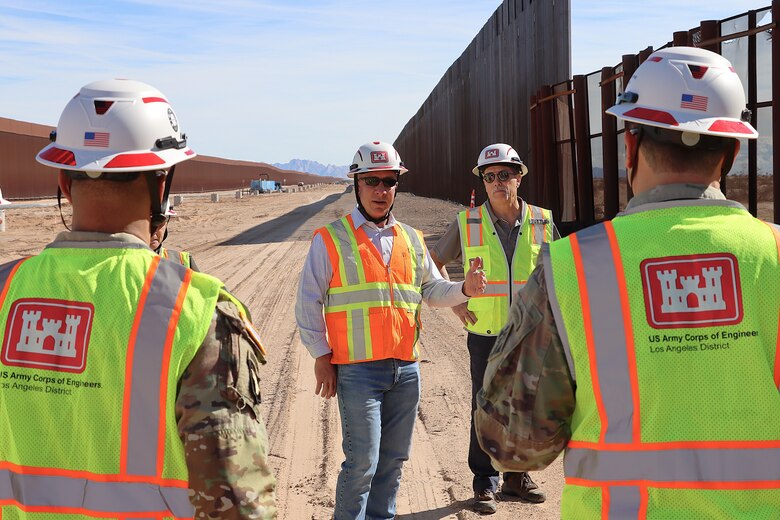 Greg Hegge, director of programs and deputy engineer of the South Pacific Border Task Force, left, and Mike Tuttle a project manager assigned to the South Pacific Border Task Force, brief panel installation progress at the BMGR-1 project site Nov. 17 near Yuma, Arizona. USACE is replacing permanent border barriers along the southern border of the U.S. at the direction of the U.S. Army by the Secretary of War, in response to the presidential national emergency declaration dated Jan. 20, 2025, authorizing the use of Section 2803 of Title 10, U.S. Code.