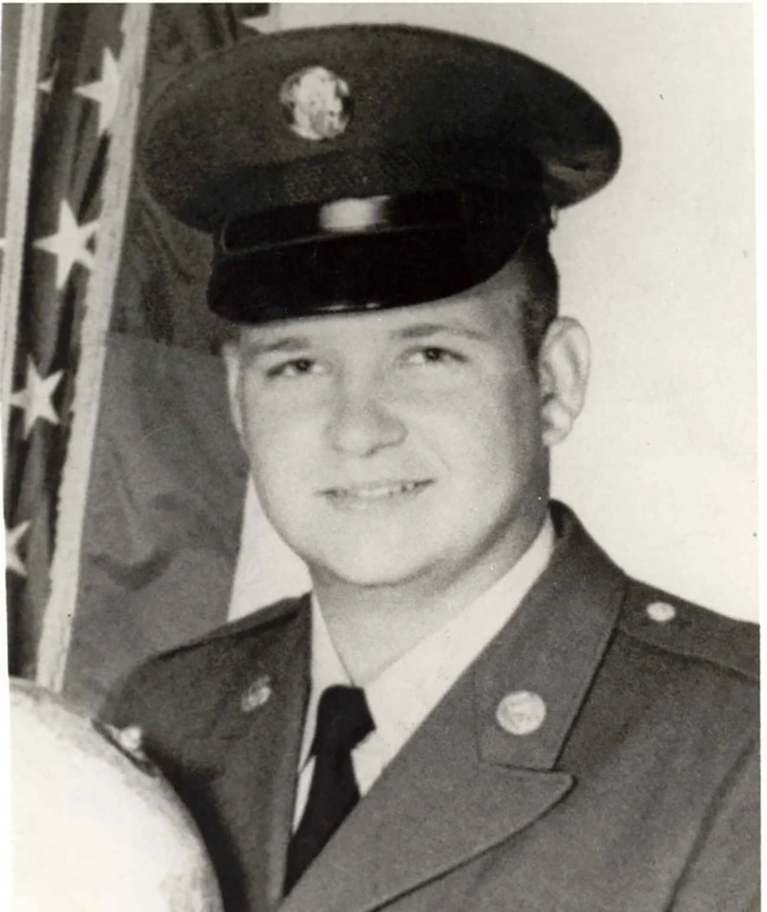 A man in a cap and military dress uniform smiles for a photo.
