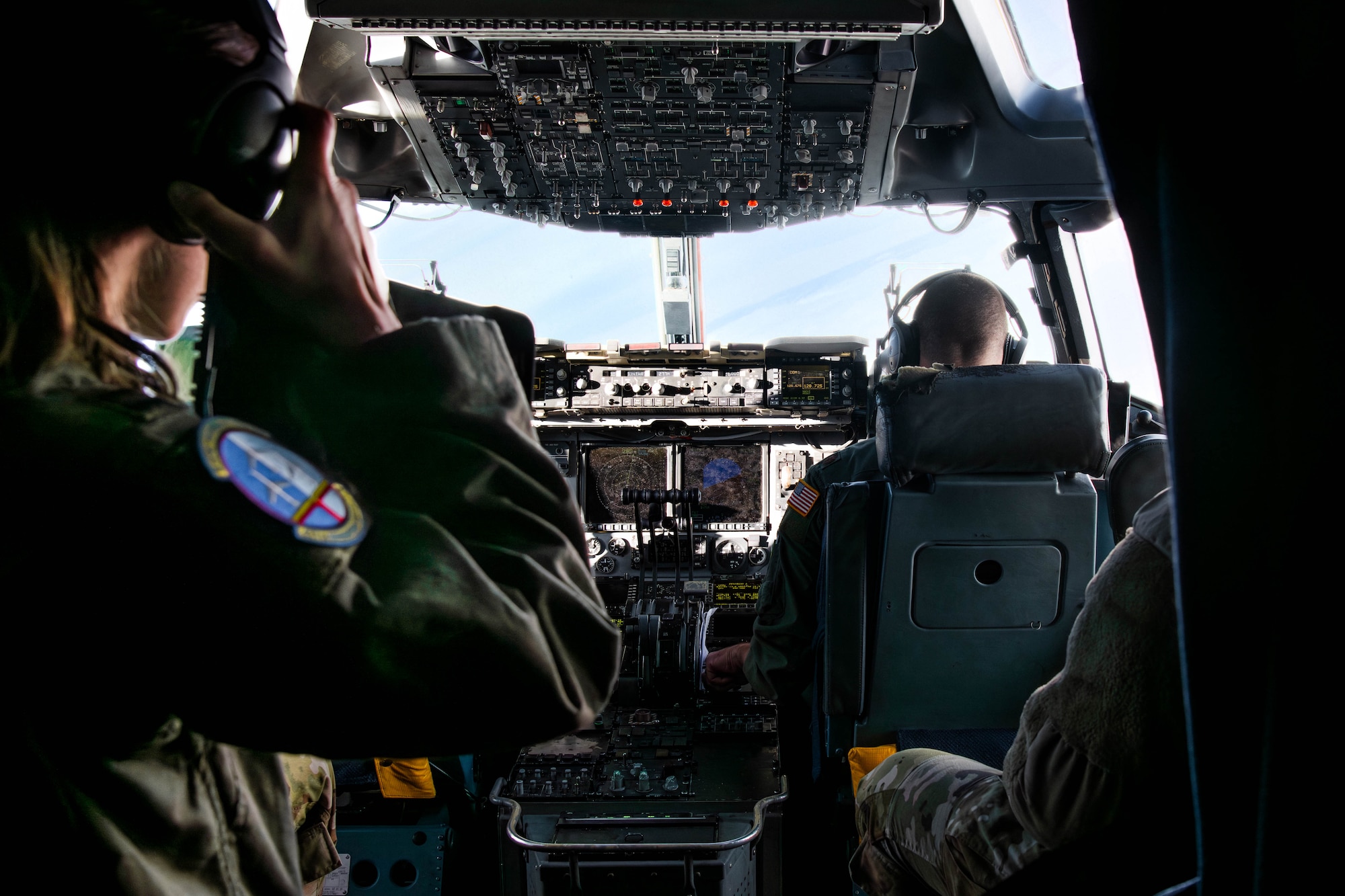 A photo of people conversing in the cockpit of a C-17 Globemaster III.