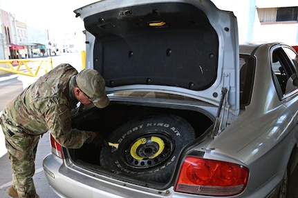 A U.S. Airman with the Arizona Air National Guard inspects a vehicle's spare tire and trunk area in a secondary search lane for drivers entering the U.S. at the Dennis DeConcini Port of Entry in Nogales, Arizona, April 29, 2025.