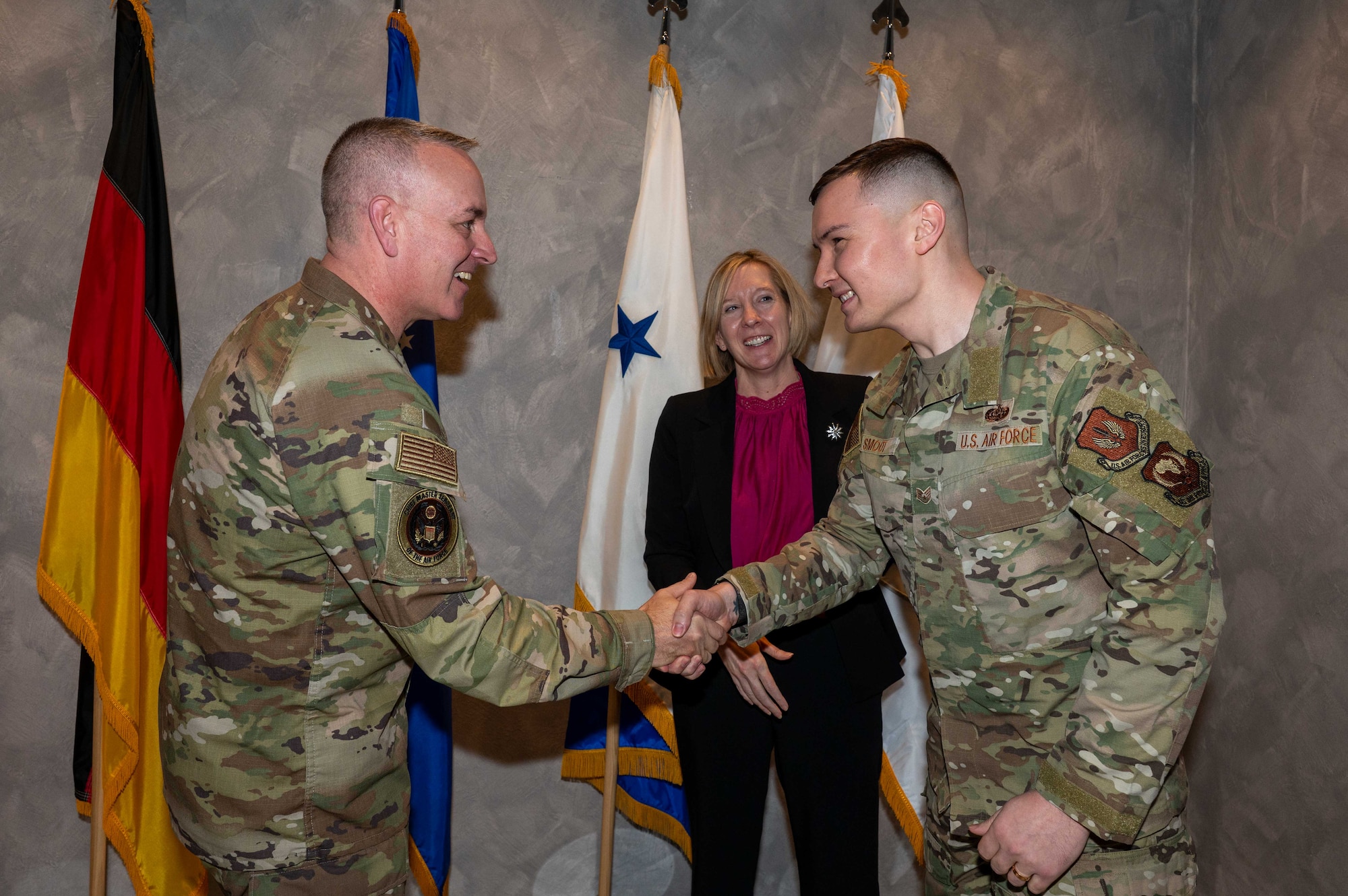U.S. Chief Master Sgt. of the Air Force David Wolfe coins Staff Sgt. Nicholas Smoot, U.S. Air Forces in Europe - Air Forces Africa noncommissioned officer in charge of Intelligence Surveillance and Reconnaissance systems support branch, at Ramstein Air Base, Germany, Dec. 23, 2025. The CSAF and CMSAF visited Ramstein AB during the holidays to emphasize that all Airmen, no matter their specialty, contribute to the generation of airpower supporting the joint fight. (U.S. Air Force photo by Airman 1st Class Rebecca Harima)