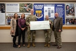Members of the Air Force Public Affairs Agency (from left to right, Ms. Annette Strapple, Ms. April Rowden and Col. Will Powell) present a $510,000 check to representatives of the Air Force Services Center (from right to left, Mr. Wallace David Collins and Col. E. Jonelle Eychner) at Joint Base San Antonio-Kelly Field Annex, Dec. 18, 2025. This event commemorates the annual contribution made by Department of the Air Force’s Trademark Licensing program to the Air Force Services Center, benefiting DAF Morale, Welfare, and Recreation programs. (U.S. Air Force photo by Staff Sgt. Harrison Winchell)