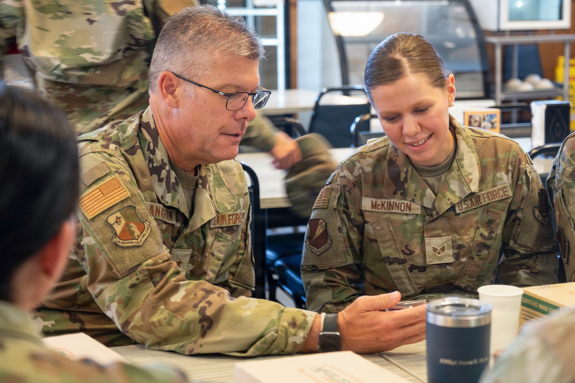Air National Guard Airmen exchange a challenge coin. They are wearing OCP Pattern uniforms.