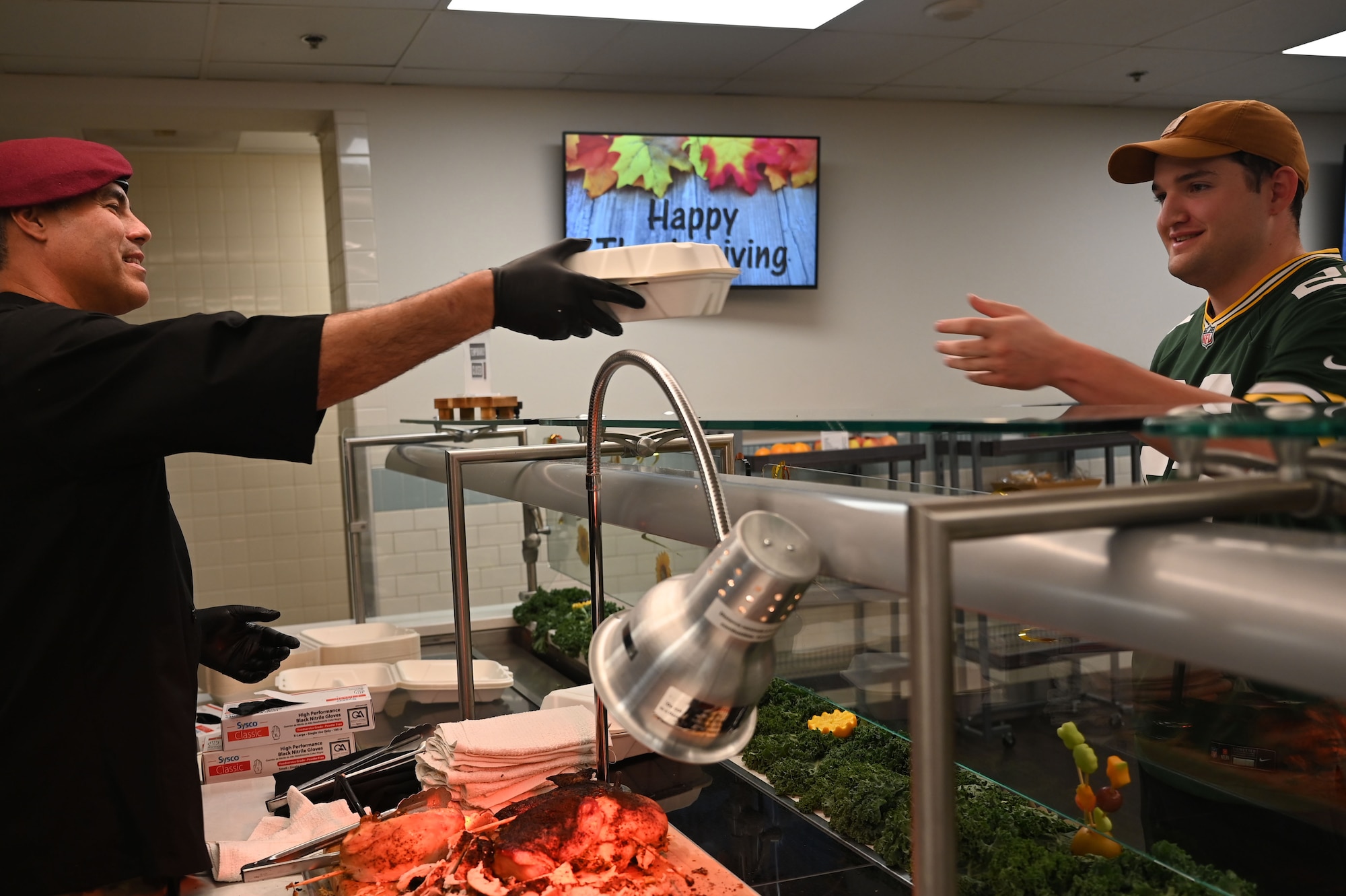 U.S. Air Force Col. Jose Cabrera, 355th Wing Commander, left, serves freshly carved turkey to Airman 1st Class Ethan Hogan, 55th Electronic Combat Group cyber security technician, on Thanksgiving day at Davis-Monthan Air Force Base, Arizona, Nov. 27, 2025. The 355th Force Support Squadron’s Desert Inn Dining Facility team prepared Thanksgiving meal options including roast turkey and gravy, baked ham with glaze, mashed potatoes, and an assortment of other side dishes. Base leaders dedicated time to help serve the Thanksgiving meal to DM service members, showing appreciation for their impact to the mission. (U.S. Air Force photo by Staff Sgt. Kahdija Slaughter)