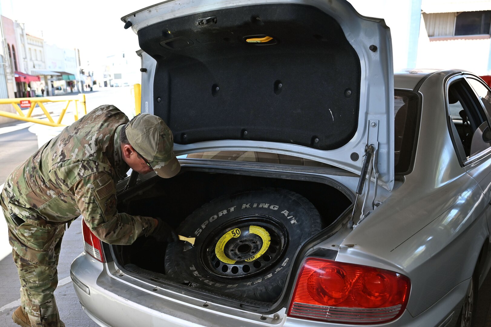A U.S. Airman with the Arizona Air National Guard inspects a vehicle's spare tire and trunk area in a secondary search lane for drivers entering the U.S. at the Dennis DeConcini Port of Entry in Nogales, Arizona, April 29, 2025.