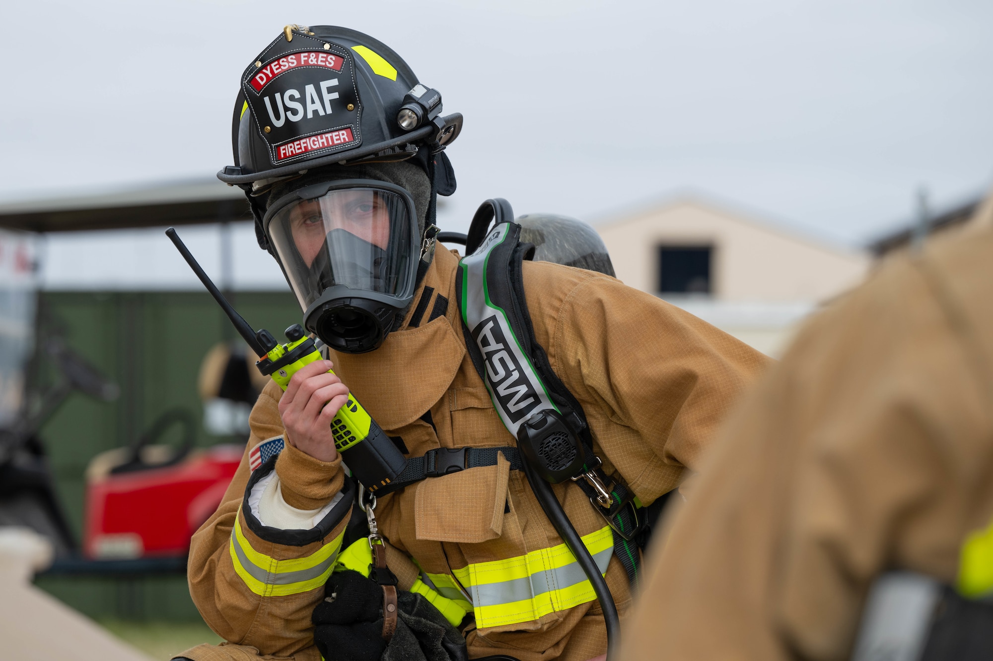A firefighter in a fire suit coordinates emergency response while outside.