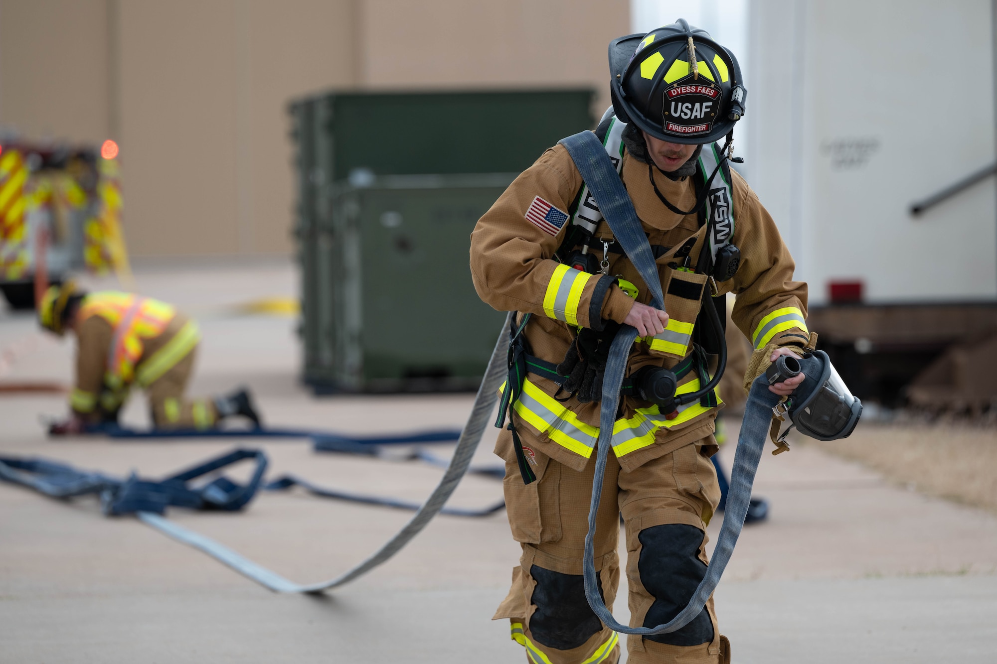 A firefighter in a fire suit coordinates emergency response while outside.