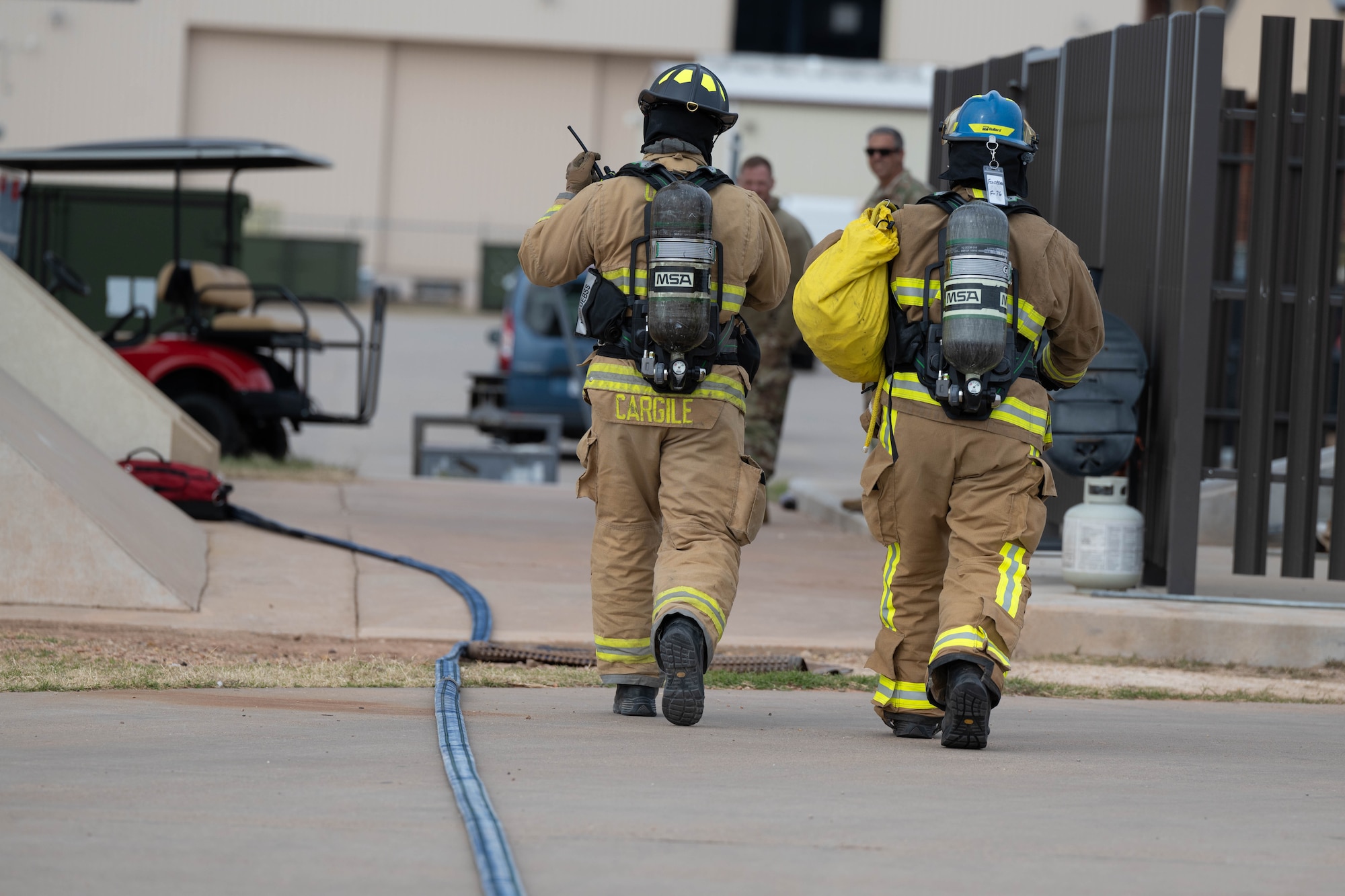 A firefighter in a fire suit coordinates emergency response while outside.
