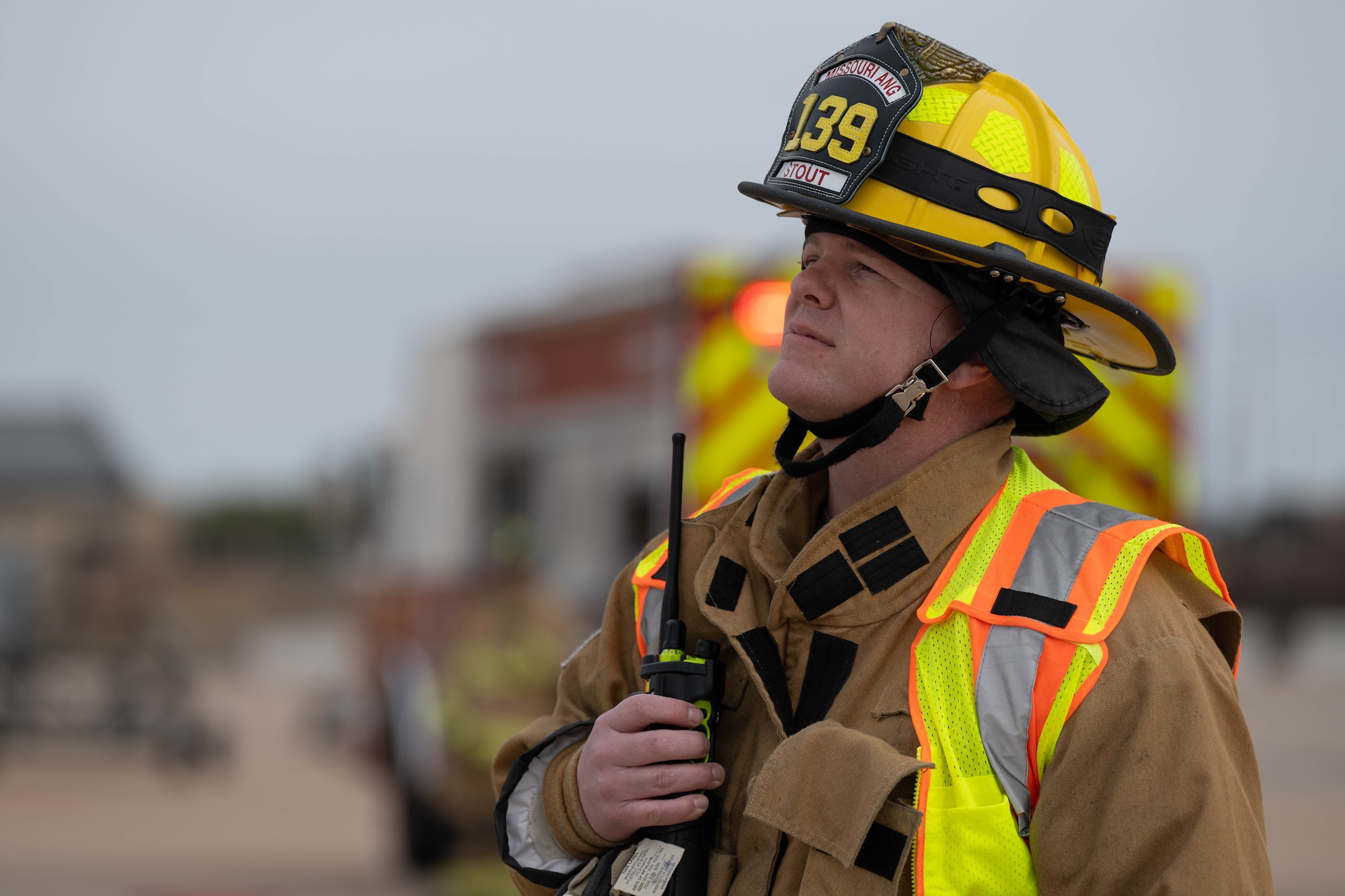 A firefighter in a fire suit coordinates emergency response while outside.
