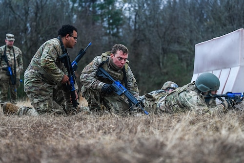 Airmen position themselves behind a barricade during a training exercise.