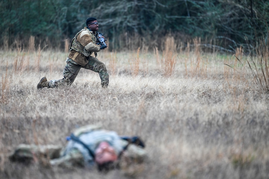 An Airman runs in a field to get to a barricade during a training exercise.