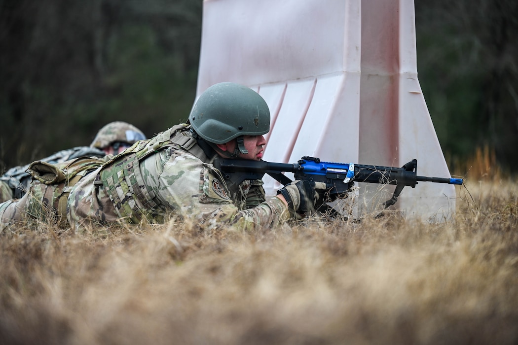 A service member wearing a helmet lies prone during a training drill.