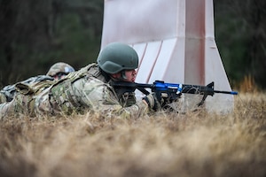 A service member wearing a helmet lies prone during a training drill.