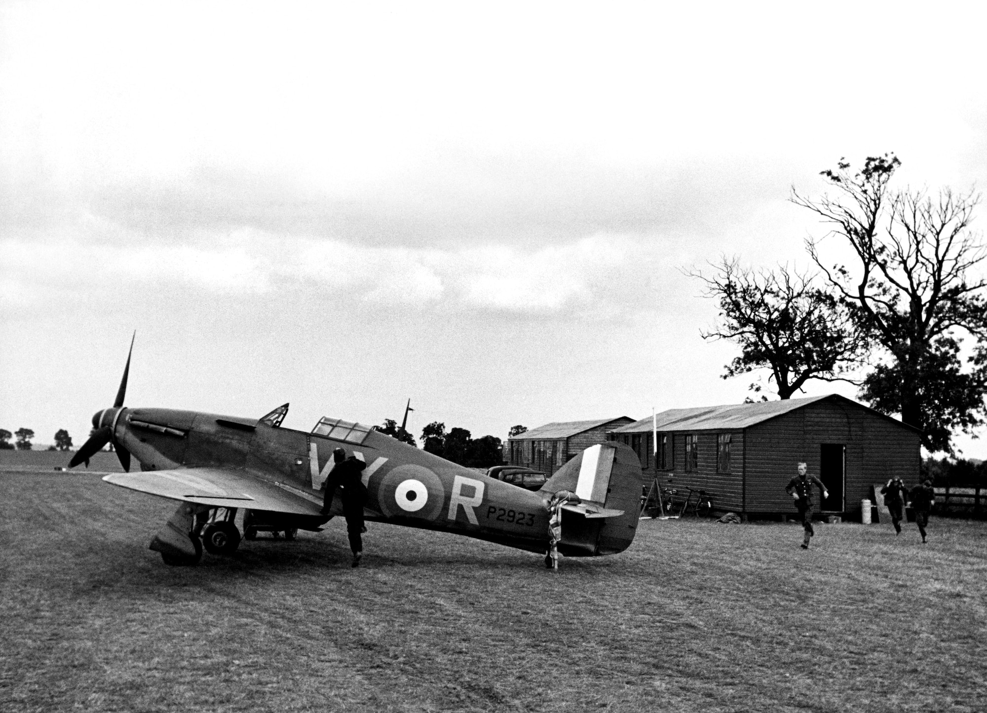 RAF pilots of No. 85 Squadron run from alert huts to their Hurricanes to meet a German attack during the Battle of Britain, July 1940. Pilots spent long hours on alert, and the hut in this exhibit is modeled on scenes like this.