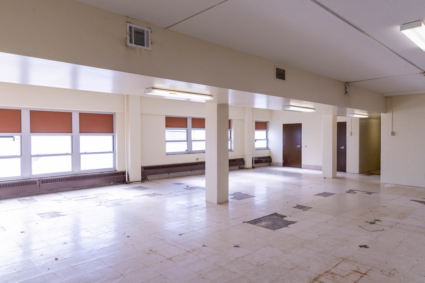 A beige room with windows and brown doors in the background.