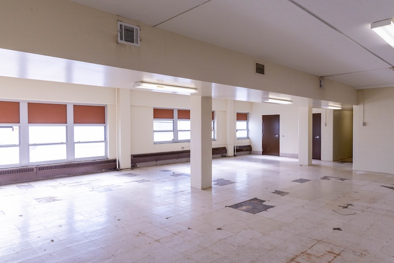 A beige room with windows and brown doors in the background.
