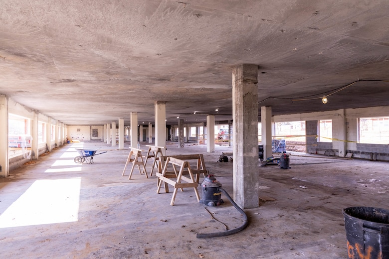 A room under construction with windows and concrete floors, walls and ceiling.