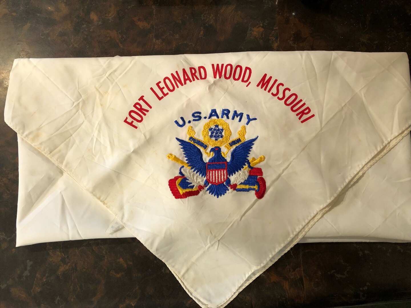 A white scarf with red, blue and yellow stitching.