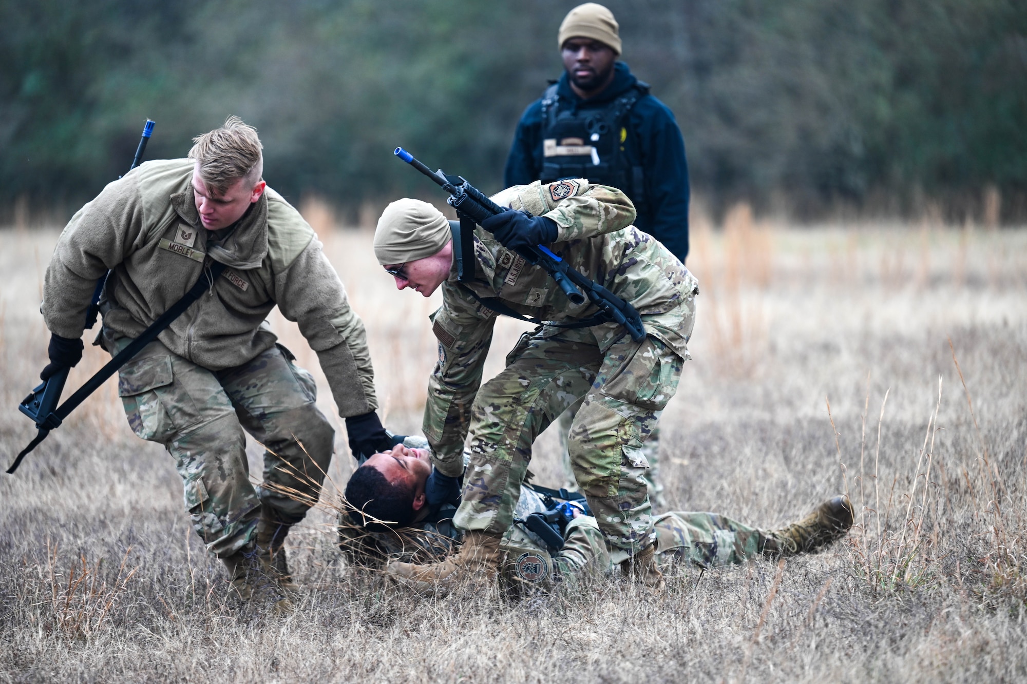 Two Airmen drag another airmen while practicing care under fire during a training exercise.