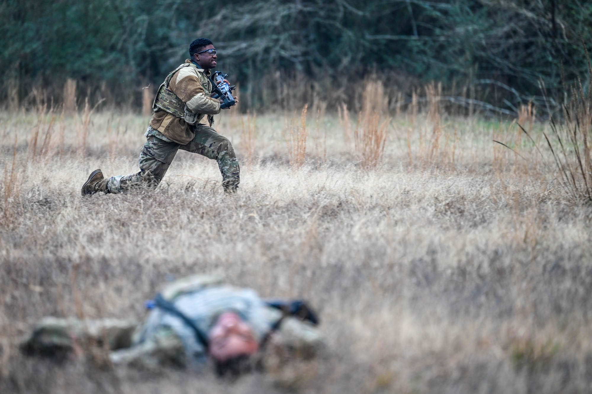 An Airman runs in a field to get to a barricade during a training exercise.