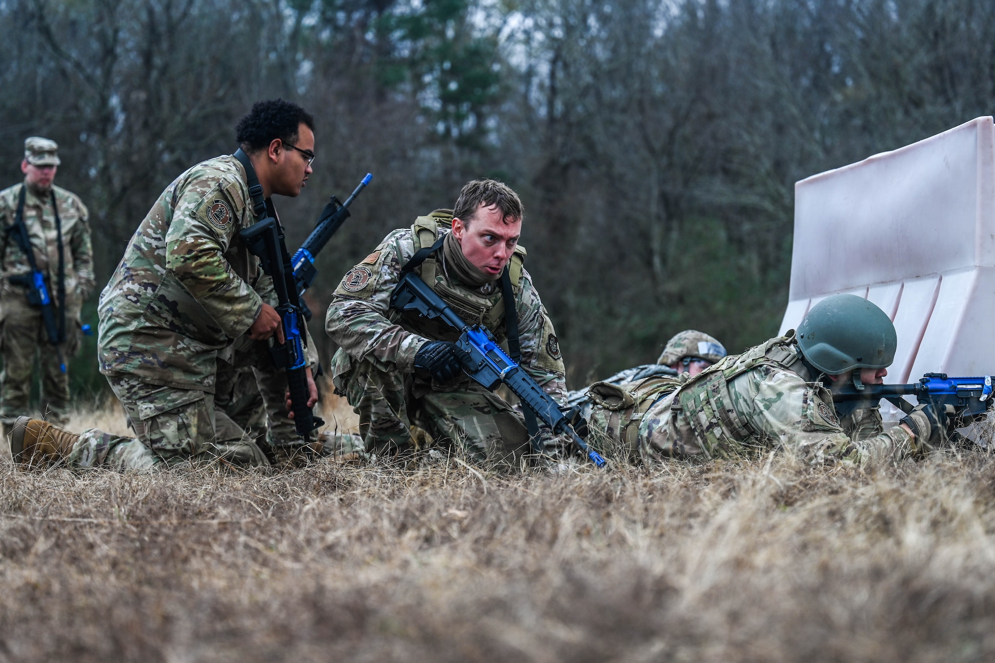 Airmen position themselves behind a barricade during a training exercise.