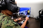 A naval aviation candidate uses a virtual reality (VR) testing station equipped with Assessing Spatial Abilities in Naval Aviation (ASANA) to gather data used in the updating and implementation of the Aviation Standardized Test Battery (ASTB) in the Naval Aerospace Medical Institute's (NAMI) behavioral research lab, Aug. 4. ASANA uses eye tracking, motion, bio metric, reaction time, and behavioral monitoring to collect data in order to pair with a user's aptitude testing data to help determine their viability as an aviation officer candidate. With five detachments, 12 training centers, and facilities in over 60 locations across the United States, NMOTC provides high impact individual medical training for the Navy, other U.S. armed forces, and allied nations around the globe. (U.S. Navy photo by Mass Communication Specialist 1st Class Russell Lindsey SW/AW)