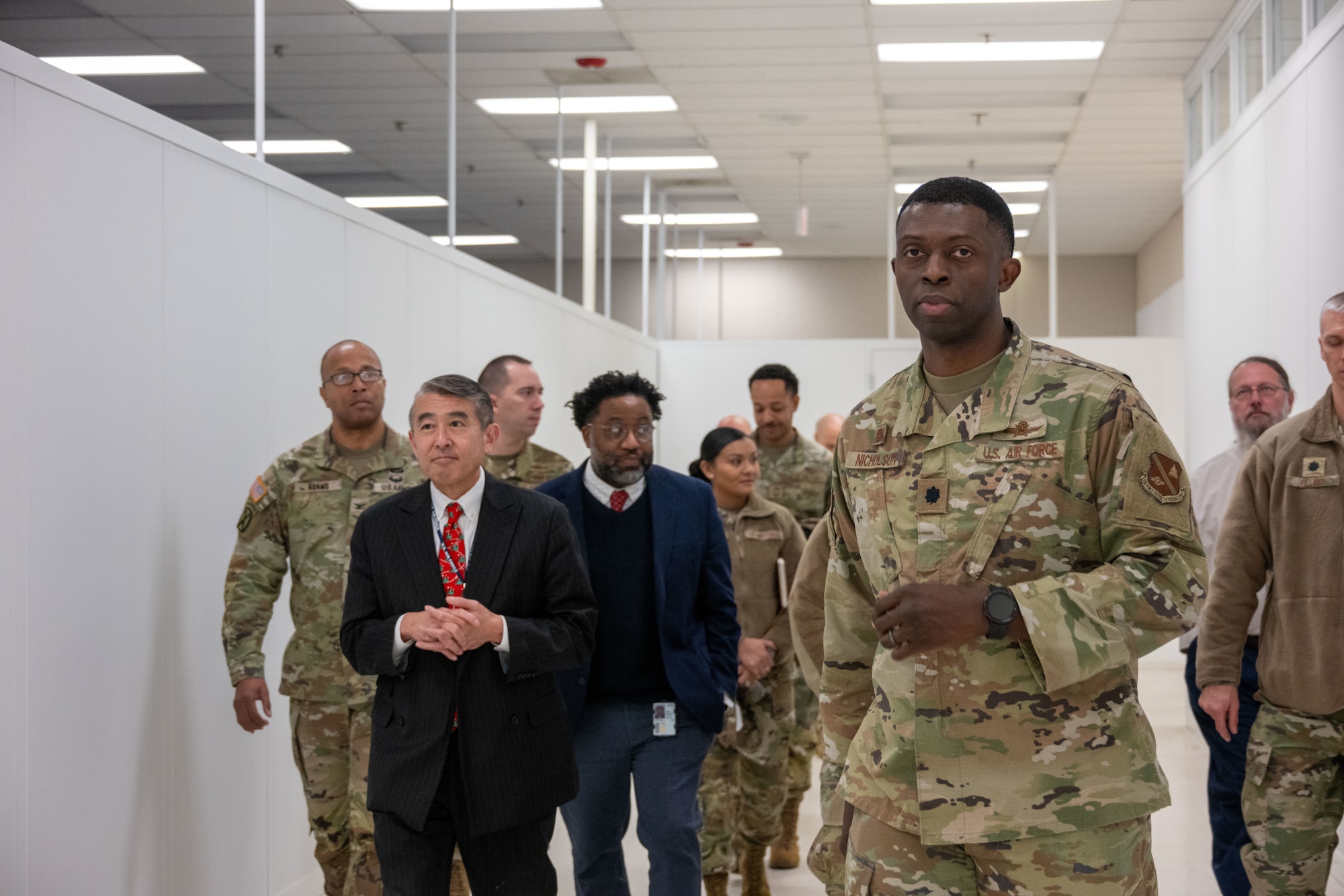 A group of military leaders walks down a hallway.