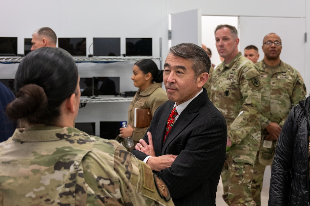 Military leaders tour a room full of computers.