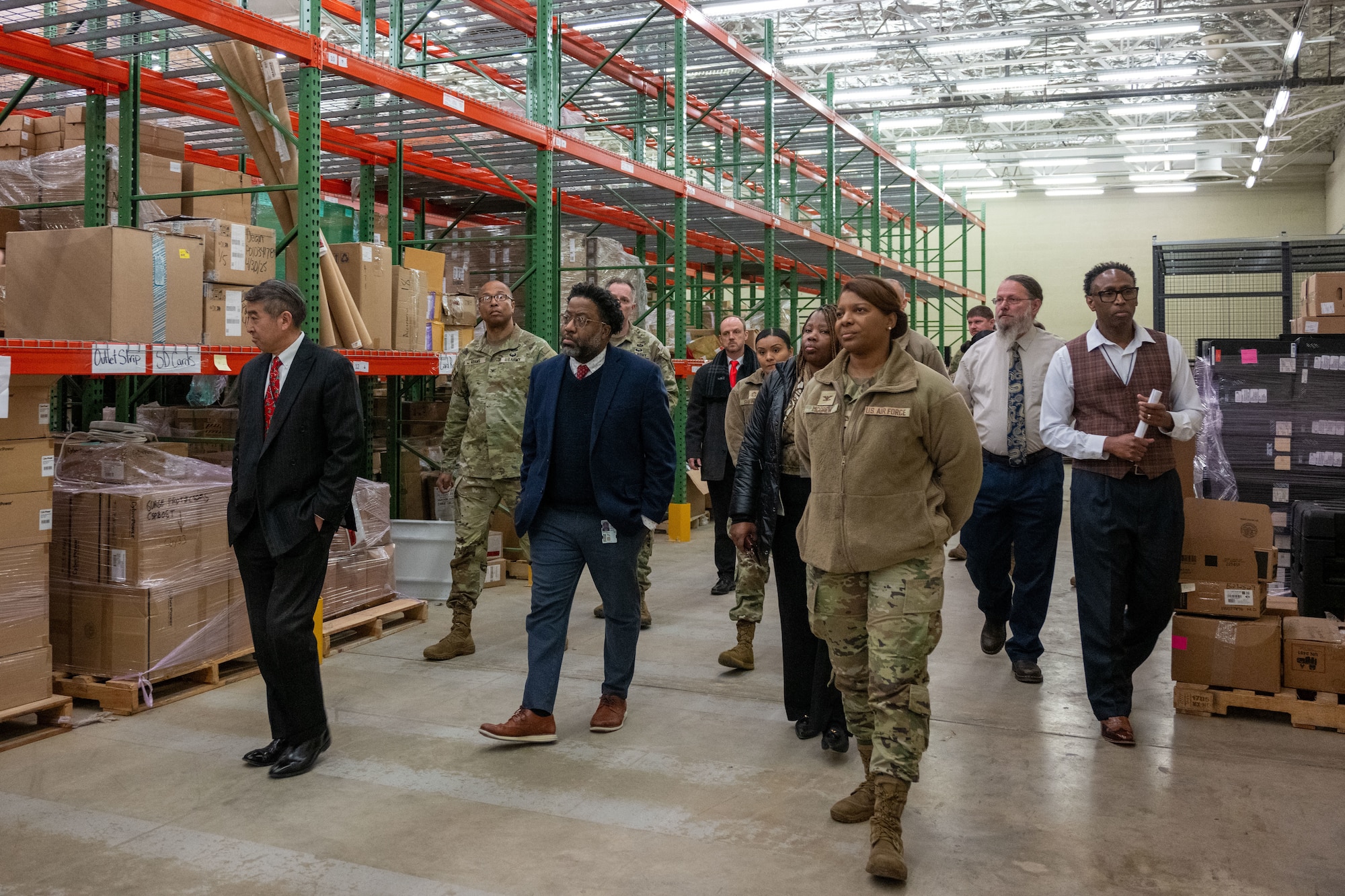 A group of military leaders tours a warehouse.