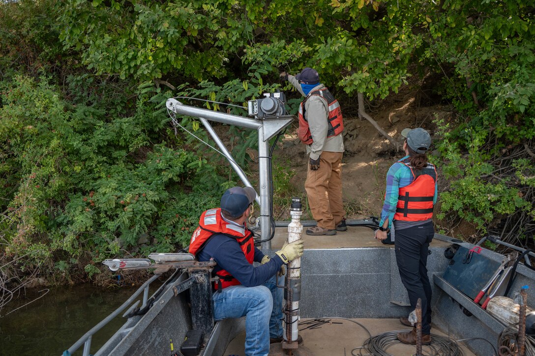 U.S. Army Corps of Engineers Sacramento District team members Aaron Siemsen, maintenance technician, David Colby, fisheries biologist, and Ashley Lopez, environmental manager, survey a site to determine the best location to secure a rope around a stable tree trunk, ensuring a Juvenile Salmon Acoustic Telemetry System (JSATS) receiver remains in place for the duration of a telemetry survey on Sept. 10, 2025, in Stockton, California. U.S. Army Corps of Engineers Sacramento District environmental managers and Bryte Yard craftsmen collaborate and conduct telemetry surveys to close critical data gaps on green sturgeon passage in the lower Sacramento River, providing valuable information to partner agencies for setting river flow requirements, managing dam releases, and improving the survival of this federally protected species.  (U.S. Army photo by Bertha Smith, U.S. Army Corps of Engineers Sacramento District Public Affairs)