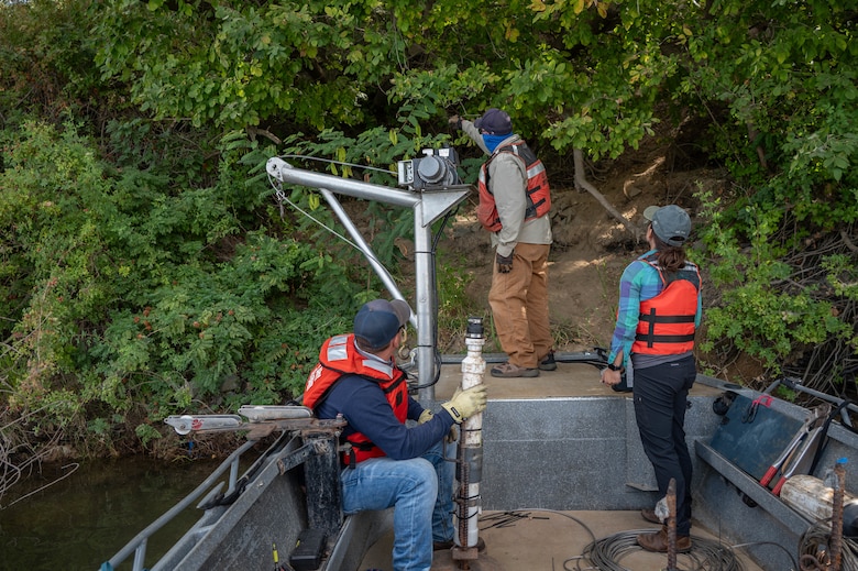 U.S. Army Corps of Engineers Sacramento District team members Aaron Siemsen, maintenance technician, David Colby, fisheries biologist, and Ashley Lopez, environmental manager, survey a site to determine the best location to secure a rope around a stable tree trunk, ensuring a Juvenile Salmon Acoustic Telemetry System (JSATS) receiver remains in place for the duration of a telemetry survey on Sept. 10, 2025, in Stockton, California. U.S. Army Corps of Engineers Sacramento District environmental managers and Bryte Yard craftsmen collaborate and conduct telemetry surveys to close critical data gaps on green sturgeon passage in the lower Sacramento River, providing valuable information to partner agencies for setting river flow requirements, managing dam releases, and improving the survival of this federally protected species.  (U.S. Army photo by Bertha Smith, U.S. Army Corps of Engineers Sacramento District Public Affairs)