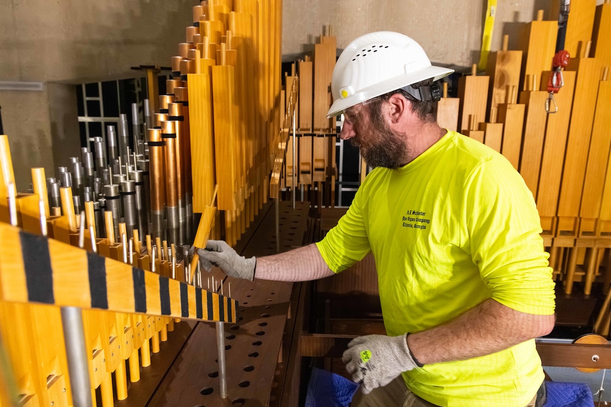 Contractor installs wooden pipe on organ