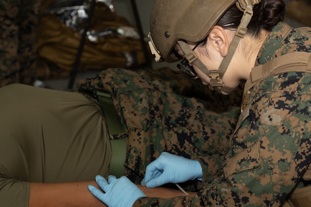 251203-M-AJ819-1006 U.S. Navy Hospital Corpsman 3rd Class Ivaniss Eason, with Headquarters Company, 3d Marine Division, inserts an intravenous needle in a volunteer’s arm during a blood transfusion class at Camp Hansen, Okinawa, Japan, Dec. 3, 2025. The Valkyrie program is a five-day course that trains Marines and sailors for emergency field blood transfusions. This skill enables corpsmen to provide life-saving blood on the battlefield from pre-screened donors, known as "walking blood banks." Eason is a native of Texas. (U.S. Marine Corps photo by Lance Cpl. Kindsey Calvert)