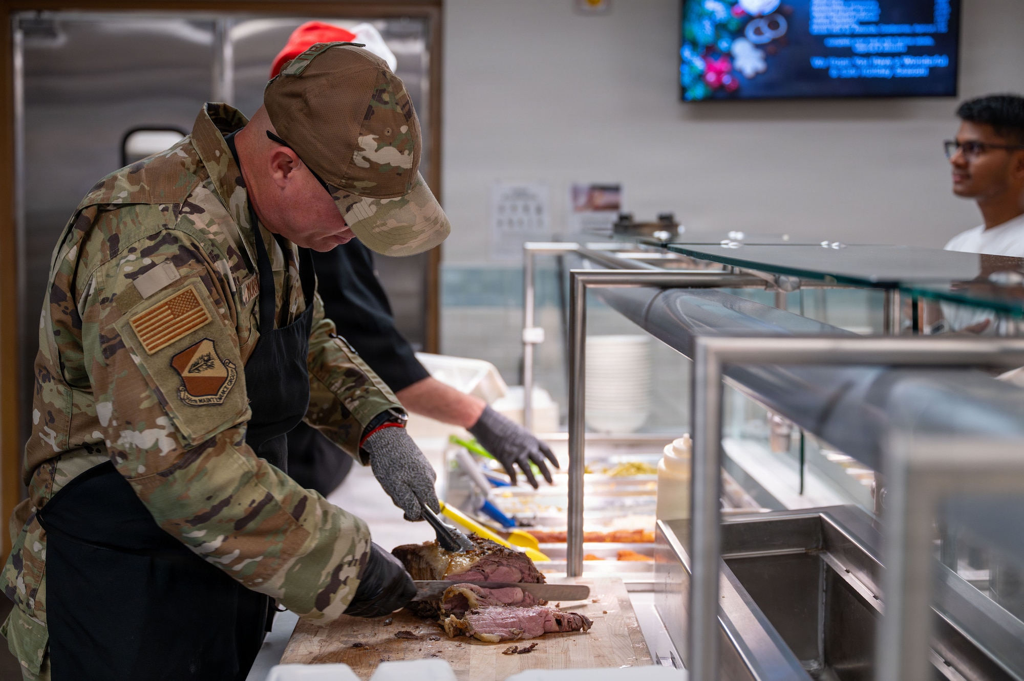 U.S. Air Force Chief Master Sgt. Christopher Morrelli, 355th Maintenance Group senior enlisted leader, prepares food to serve at Davis-Monthan Air Force Base, Arizona, Dec. 25, 2025. The dining facility offered a holiday meal to members of the Desert Lightning Team. (U.S. Air Force photo by Senior Airman Jasmyne Bridgers-Matos)