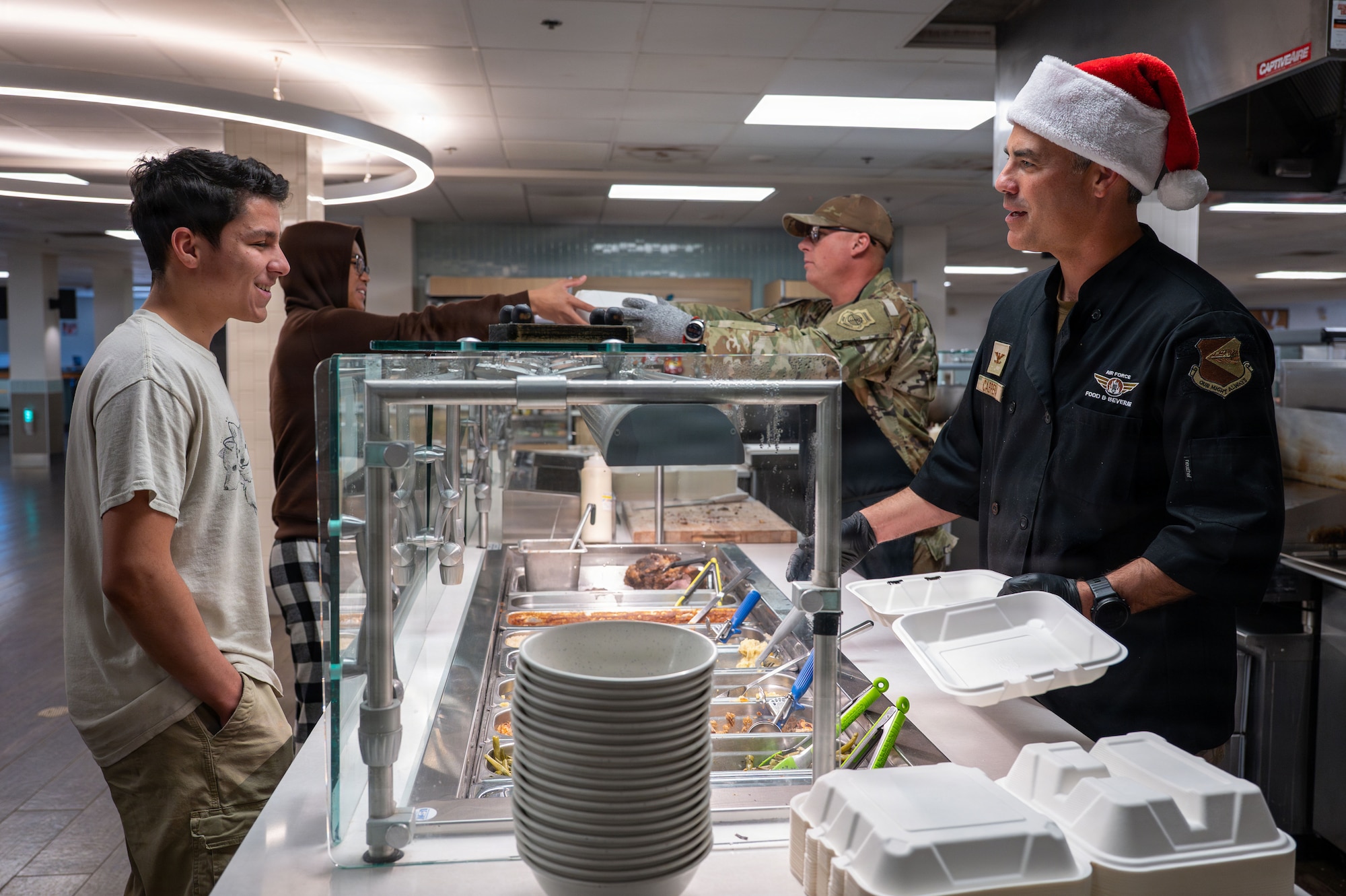 U.S. Air Force Col. Jose Cabrera, 355th Wing commander, and Chief Master Sgt. Christopher Morrelli, 355th Maintenance Group senior enlisted leader, serve Airmen a holiday meal at 
Davis-Monthan Air Force Base, Arizona, Dec. 25, 2025. The dining facility team and base leadership coordinated to serve Airmen a meal on Christmas. (U.S. Air Force photo by Senior Airman Jasmyne Bridgers-Matos)