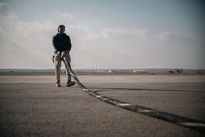 U.S. Air Force Airman 1st Class Samuel Ilet, 332nd Expeditionary Logistics Readiness Squadron fuels distribution operator, moves a fuel hose into position in the U.S. Central Command area of responsibility, Dec. 14, 2025.