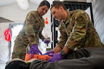 Staff Sgt. Blanca Sanchez, 19th Medical Group medical technician, and Maj. Skylar McMath, 19th Combat Airbase Squadron physical therapist, secure a splint to a leg wound during a mass casualty (MASCAL) scenario on Joint Base San Antonio-Camp Bullis, Texas, Dec. 18, 2025. The MASCAL scenario was the culmination event for a Rehearsal of Concept, and validated a new framework confirming a Unit of Action’s ability to rapidly establish medical support on a bare base and provide Role 1 medical care. (U.S. Air Force photo by Joshua J. Garcia)