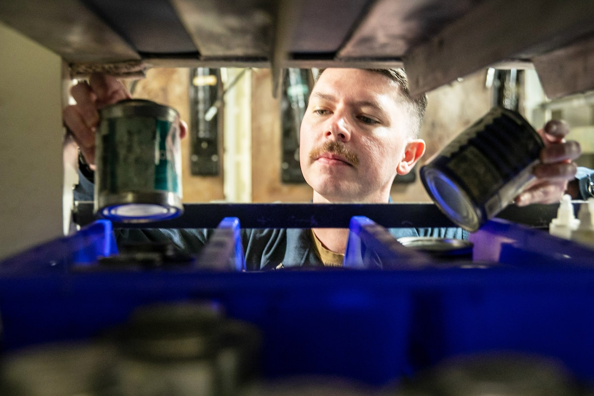 A close-up of a sailor counting cans in a locker.