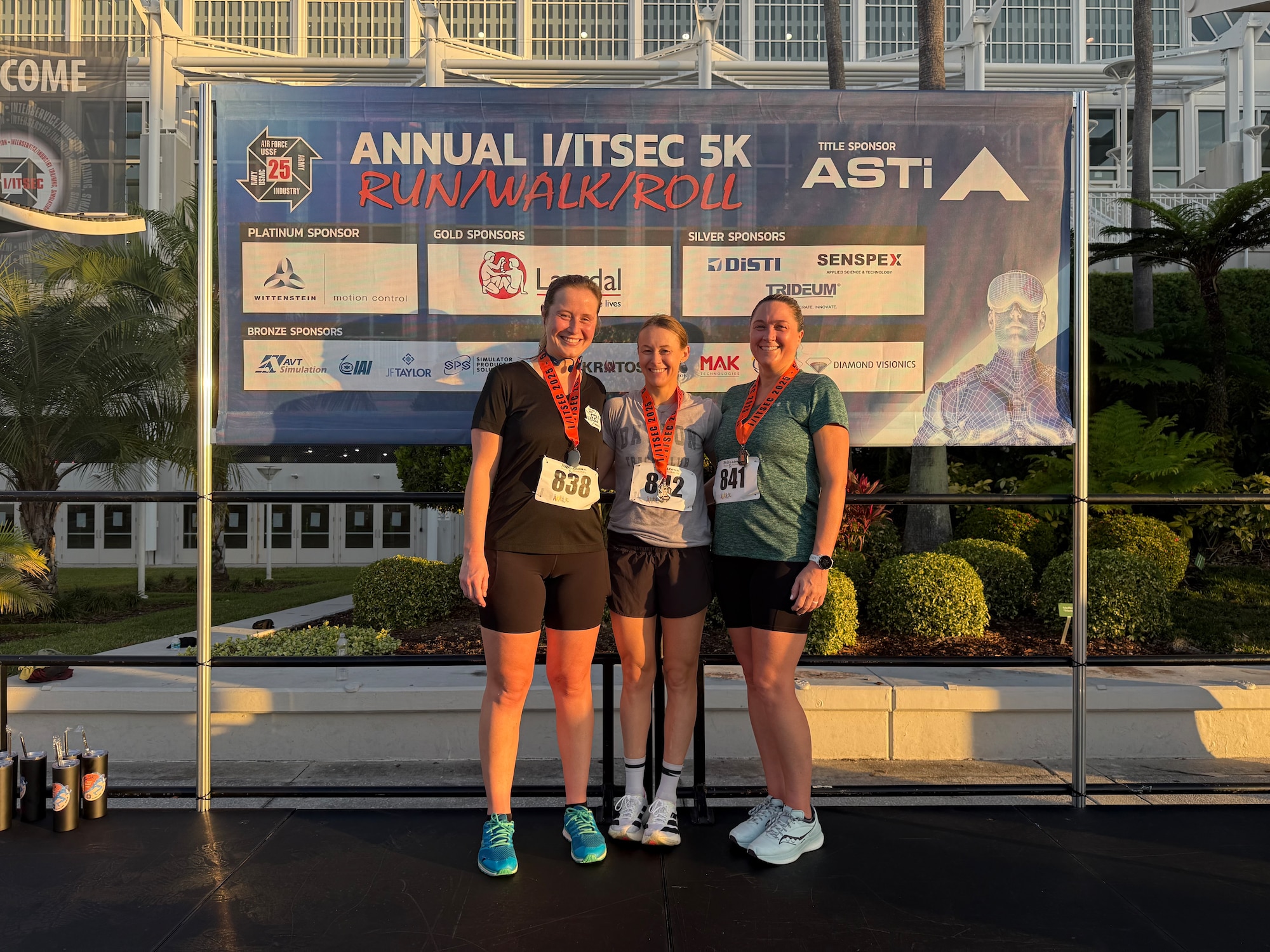 Lindsay Babish, an Air Force Life Cycle Management Center (AFLCMC) Training Directorate F-16 Simulator Training Program lead program manager, poses for a photo with coworkers after a 5K race in Orlando, Florida, Dec. 2025. Babish attended the annual Interservice/Industry Training, Simulation and Education Conference (I/ITSEC) and participated in the 5K run, “Walk and Roll”. (Courtesy Photo)