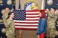 Soldier and Future Soldier pose in front a flag.