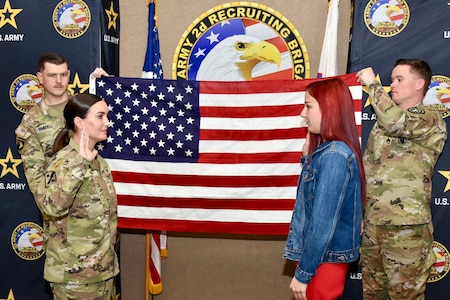 U.S. Army Maj. Lauren Hall administers the Oath of Enlistment during a ceremony for Sophie Marie Stewart on Jan. 29, 2025, while recruiters, Sgt. 1st Class Chuck Vandell (left) and Staff Sgt. Chance Schutter (right), hold the U.S. flag at U.S. Army 2nd Recruiting Brigade, Redstone Arsenal, AL. Stewart enlisted as a 68T Animal Care Specialist, taking the first steps towards fulfilling her dream of a career in the medical field.