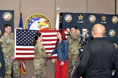 U.S. Army Maj. Lauren Hall, congratulates Sophie Marie Stewart at the conclusion of her Oath of Enlistment Ceremony, Jan. 29, 2025 at Redstone Arsenal, AL. In the foreground is Naji Shaheed, 2nd BDE Social Media Specialist capturing the moment for livestream viewers, and in the background are Stewart’s recruiters, Sgt. 1st Class Chuck Vandell and Staff Sgt. Chance Schutter from U.S. Army Recruiting Station Huntsville-Madison.