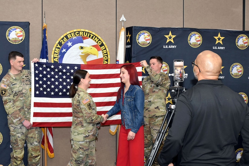 U.S. Army Maj. Lauren Hall, congratulates Sophie Marie Stewart at the conclusion of her Oath of Enlistment Ceremony, Jan. 29, 2025 at Redstone Arsenal, AL. In the foreground is Naji Shaheed, 2nd BDE Social Media Specialist capturing the moment for livestream viewers, and in the background are Stewart’s recruiters, Sgt. 1st Class Chuck Vandell and Staff Sgt. Chance Schutter from U.S. Army Recruiting Station Huntsville-Madison.