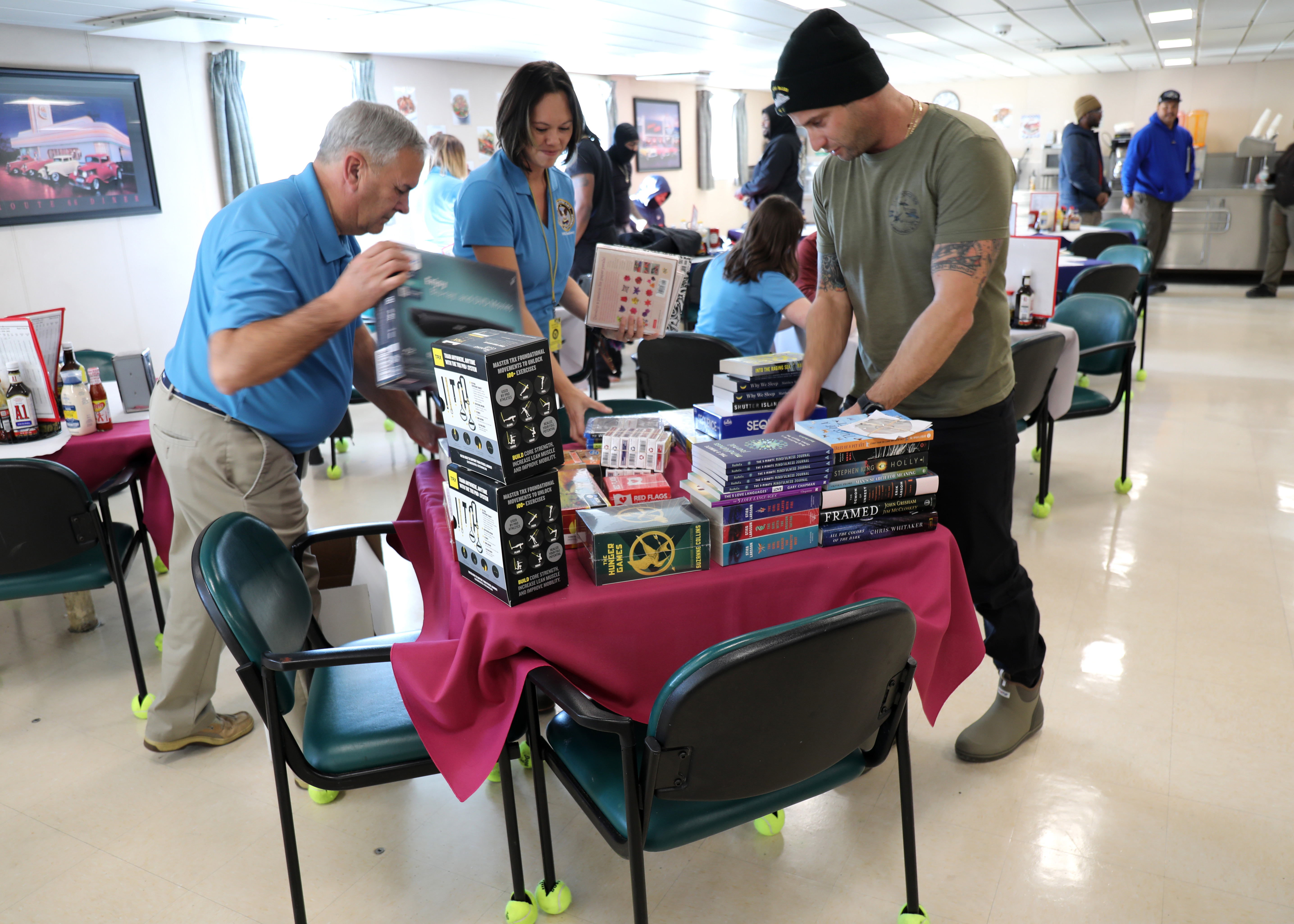 Capt. Adam Streeper, Master of Military Sealift Command's dry cargo ammunition ship USNS William McLean (T-AKE 12) (right) browses through the contents of a crew care package with Chris Baker, MSC Afloat Workforce Development Instructional Systems Specialist (left) and Erin Sager, MSC Afloat Workforce Development Civilian Mariner Training Development (center) while the ship was pier-side on Naval Station Norfolk, Jan. 13. The crew care package delivery was part of the MSC The Resiliency/Health Promotion Team's visit to the ship to assist with building and maintaining crew resiliency.
