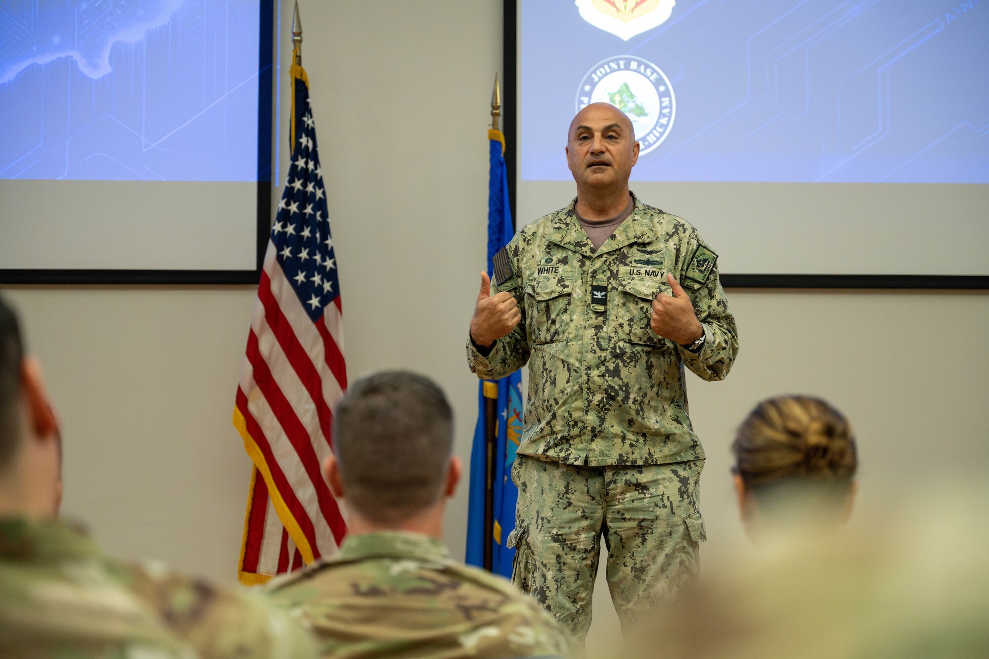 Sailor speaks in front of a crowd of servicemembers.