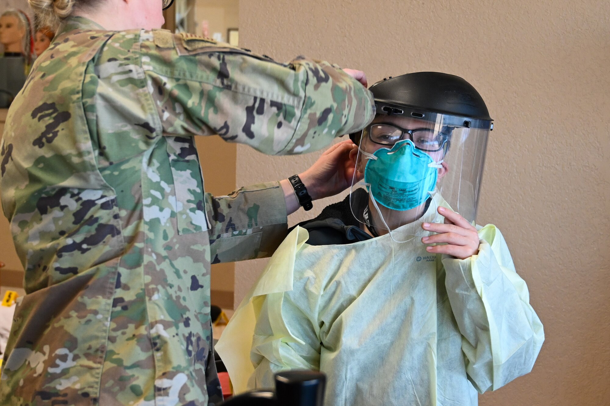 U.S. Air Force Maj. Mary Marks Nelson, 97th Healthcare Operations Squadron pediatrician, secures a facial shield on a student's head during a Science, Technology, Engineering, Arts, and Math (STEAM) fair at Southwest Technology Center at Altus, Oklahoma, Jan. 22, 2025. This collaborative STEAM fair hosted more than 160 students from seven schools around Southwest Oklahoma. (U.S. Air Force photo by Airman 1st Class Lauren Torres)