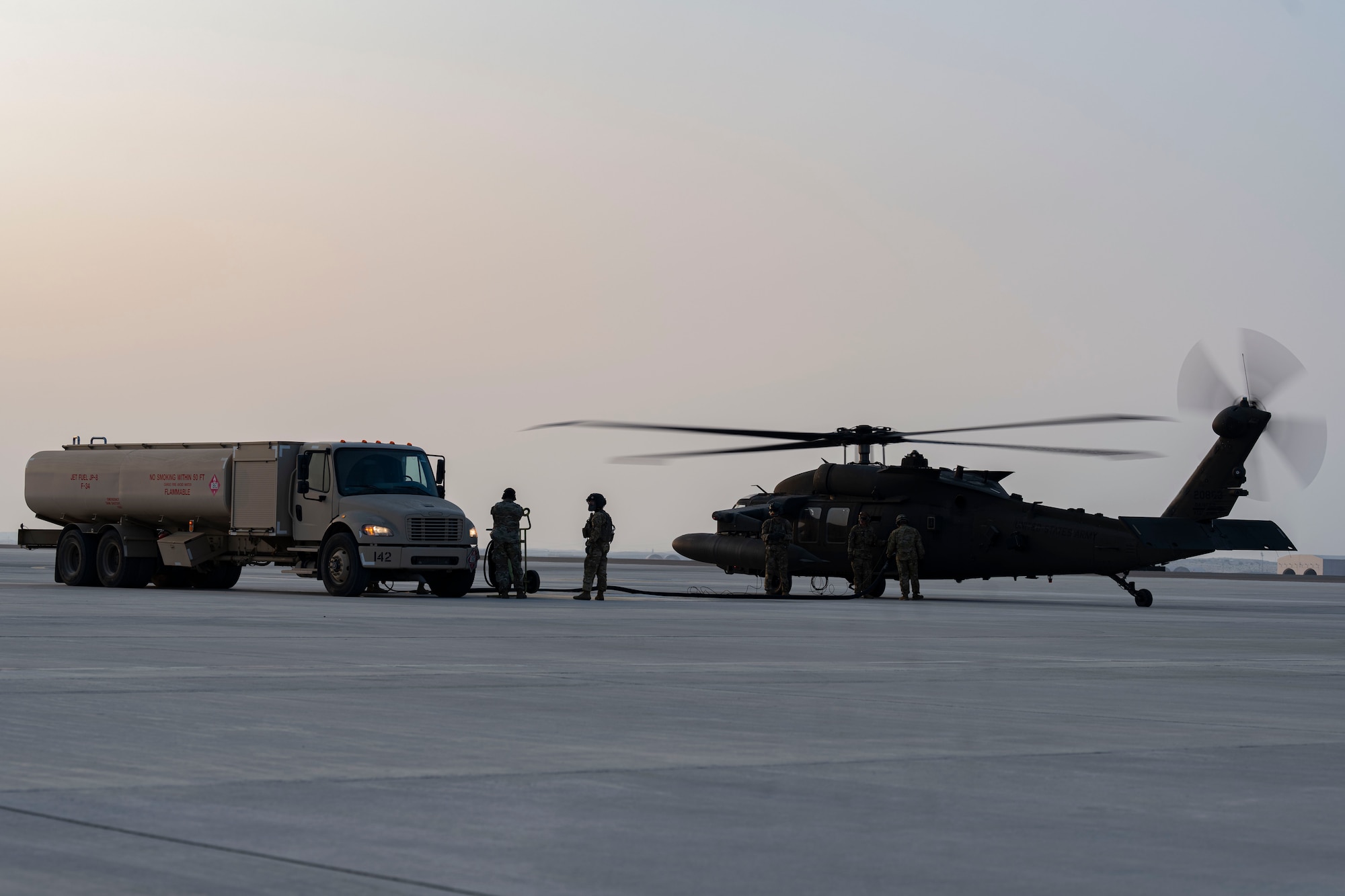 Soldiers and Airmen refuel helicopter.