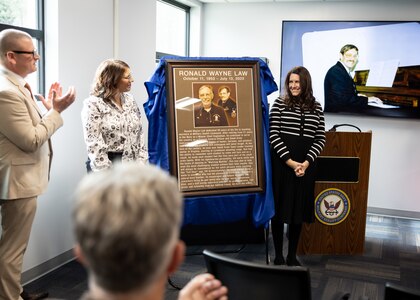 The plaque dedicated to Ronald “Ron” Law is unveiled during the Ron Law Small Arms Marksmanship Training Center (SAMTC) building dedication, held in the building Jan. 23, 2025. The building has been named after Ronald “Ron” Law, who dedicated 30 years of his life to Military Sealift Command as a Damage Control Officer and Small Arms Instructor.