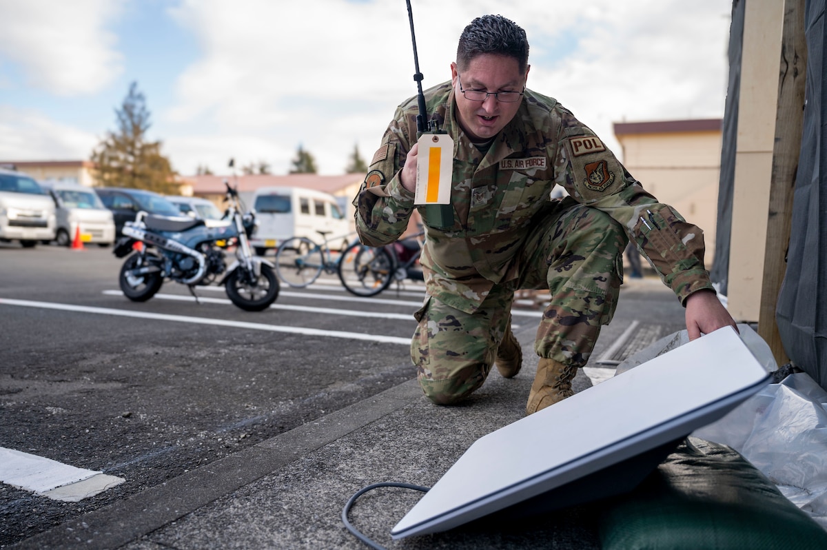 Service member talks on radio while setting up satellite.
