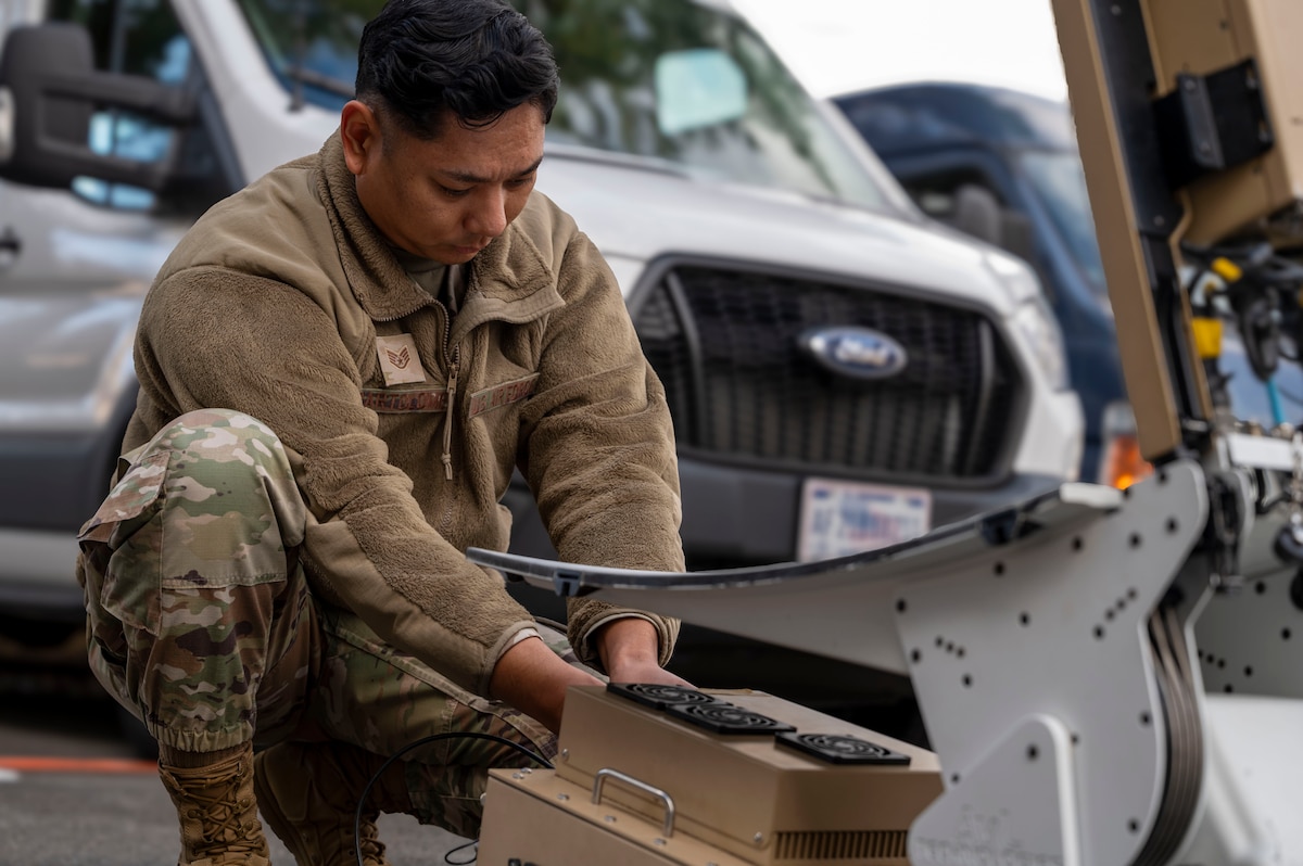 Service member works on satellite.